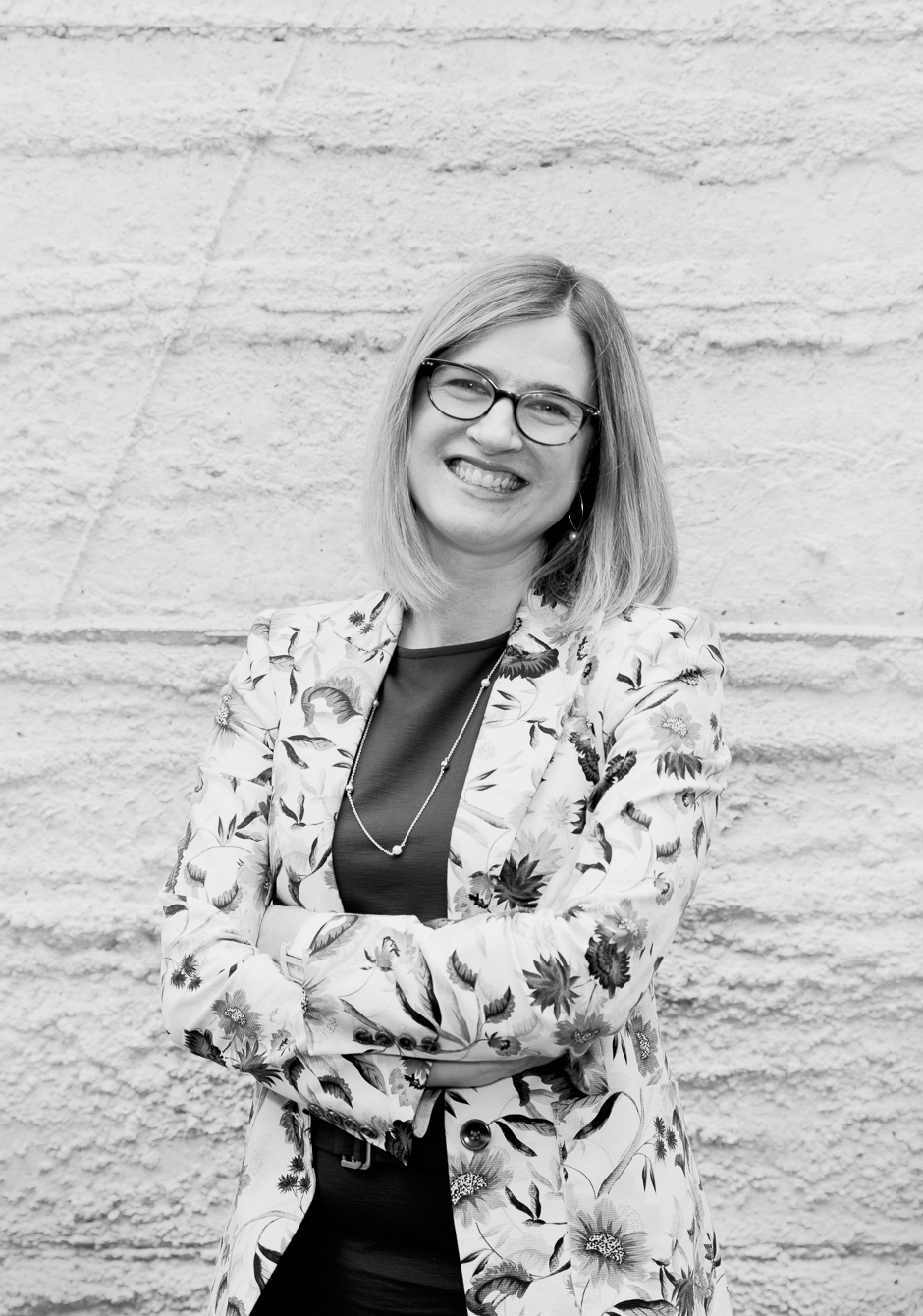 A woman stands with her arms crossed. She is smiling and facing the camera.