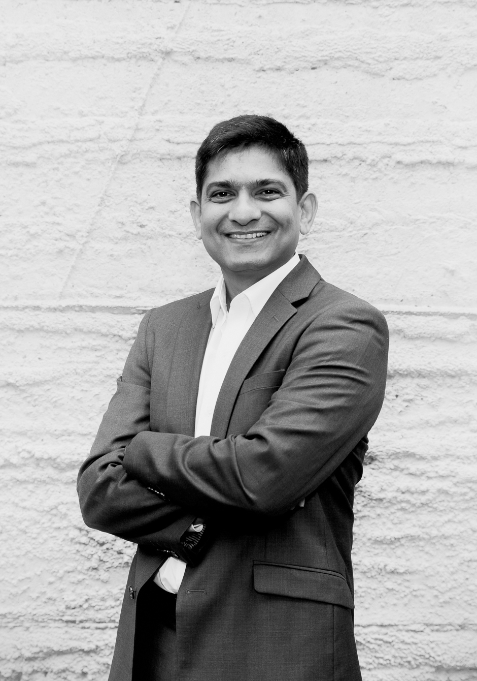 A man stands with his arms crossed. He is facing the camera and smiling.